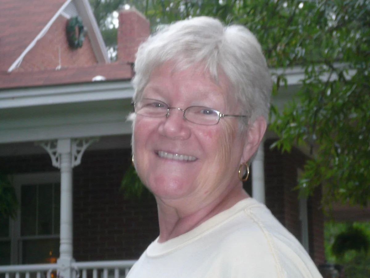 Yvonne smiling in front of the porch at Heartfriends Inn